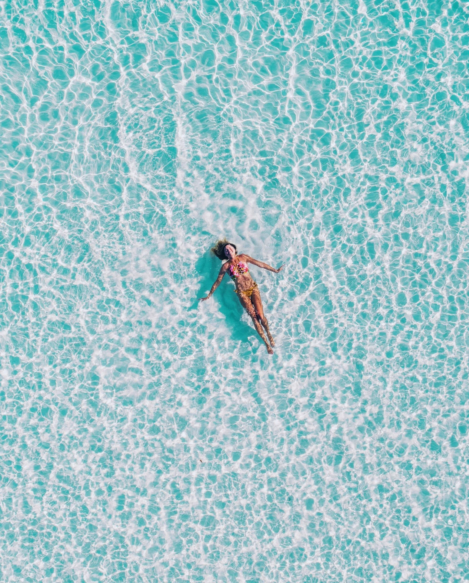 A picture of a woman floating in a big pool.